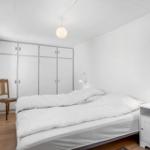 Bedroom with bed, nightstand, wardrobe, and chair.
