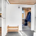 Entrance area with closet, wooden bench, and view into kitchen and bedroom.