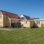 A yellow house with a red roof and green lawn under a blue sky.