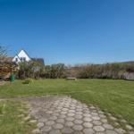 Backyard with grass area, stone path, and white fence.