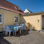 Backyard with table, chairs, and entrance door. Yellow walls and red roof.