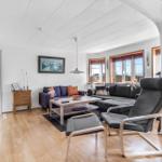 Living room with sofa, chair and wooden floor. Windows with view outside.