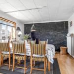 Dining room with wooden table, striped chairs, and stone wall in background.
