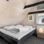 Bedroom with wooden walls, bed, window, and bedside table.