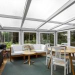 Terrace with seating, dining table, and grill. Fully glazed with garden view.