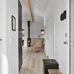 Hallway with wooden floor, white walls, seating area, and fireplace in the background.