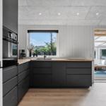 Kitchen with black cabinets, wooden countertop, and view of the garden.