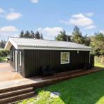 Wooden house with deck, garden, and tree view under blue sky.