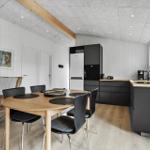 Kitchen with dining area, black cabinets, wooden table and chairs, wall art, and window.