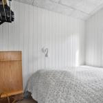 Bedroom with bed, window, and wooden shelf on the wall.