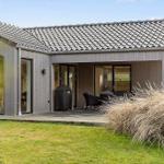 Modern villa with terrace, grill, and glass facades. Lawn and shrubs in the foreground.