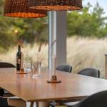 Dining table with chairs, candles, and wine by large window overlooking grass.