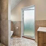 Bathroom with shower, toilet, and sink with wooden vanity.