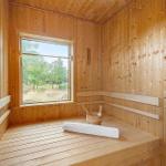 Wooden sauna with window, bucket, and bench.