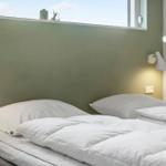 A bed with white pillows and a duvet. Two wall-mounted lamps are visible.