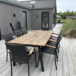 Deck with wooden table and eight chairs in front of modern house