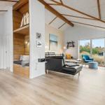 Living area with wooden ceiling, sofa, fireplace, and view of greenery.