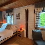 Schlafzimmer mit Bett, Nachttisch, Stuhl und Fenster mit Vorhängen.