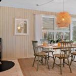 Esszimmer mit Holztisch, Stühlen und Kaminofen. Fenster zeigen Wald.
