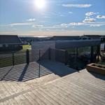 Holzterrasse mit Blick auf das Meer und moderne Häuser.