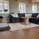 Großer Wohnbereich mit dunklem Sofa, Holzboden und runden Tisch.