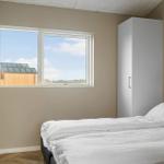 Schlafzimmer mit weißem Bett, Kleiderschrank und Fensterblick auf Holzhaus.