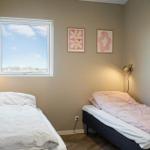 Zwei Betten mit Bettwäsche, Fenster und Wandbilder.