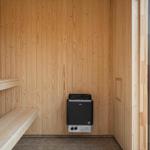Sauna mit Holzwand und Sitzbank sowie Heizgerät.