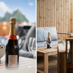 Terrasse mit Holztisch, Flasche Sekt und Gläsern vor Holzwand
