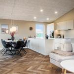 Wohn- und Essbereich mit Kücheninsel, Esstisch und Sofa.