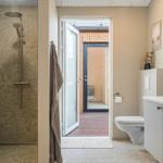 Bad mit Dusche, Toilette und Waschbecken. Durchgang zur Terrasse mit Holzdecke.