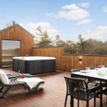 Terrasse mit Sauna, Whirlpool, Liegestühlen und Esstisch.