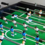 Foosball table with blue and white players on green field.