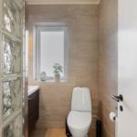 Bathroom with toilet, window, and glass block wall