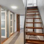 Hallway with wooden staircase, door, and refrigerator visible