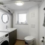 Bathroom with washing machine, toilet, and round mirror
