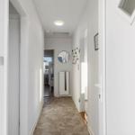 Hallway with stone floor, mirror, and radiator on the wall.