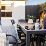 Outdoor area with table, chairs, cushions, and thermos.