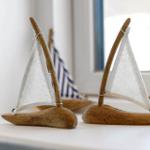 Two wooden sailboats with white sails are on a windowsill.