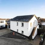 A white house with a black roof and outdoor stairs.