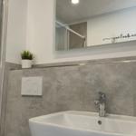 Bad mit Dusche, Waschbecken und Spiegel mit Aufschrift.