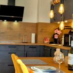 Küche mit Esstisch, hängenden Lampen und Weinflasche.