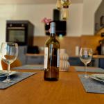 Esstisch mit Weinflasche und Gläsern, Küchenbereich im Hintergrund.