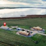 Drei Häuser auf einer grünen Wiese neben einem See