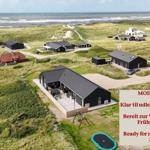 Moderne Ferienhaus mit Terrasse und Trampolin auf Dünenlandschaft. Bereit zur Vermietung im Frühling 2026.