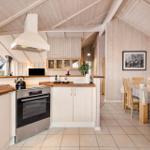 Kitchen with dining area, wooden walls, and stone tile floor.