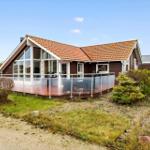 Modern house with terrace and glass railing. Surrounded by grass and shrubs.