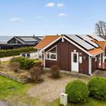 A brown house with solar panels overlooking the water.