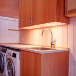 Kitchen area with sink, washing machine, and wooden fixtures.