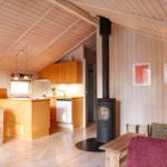 Living kitchen with wood walls, wood stove, and dining area.